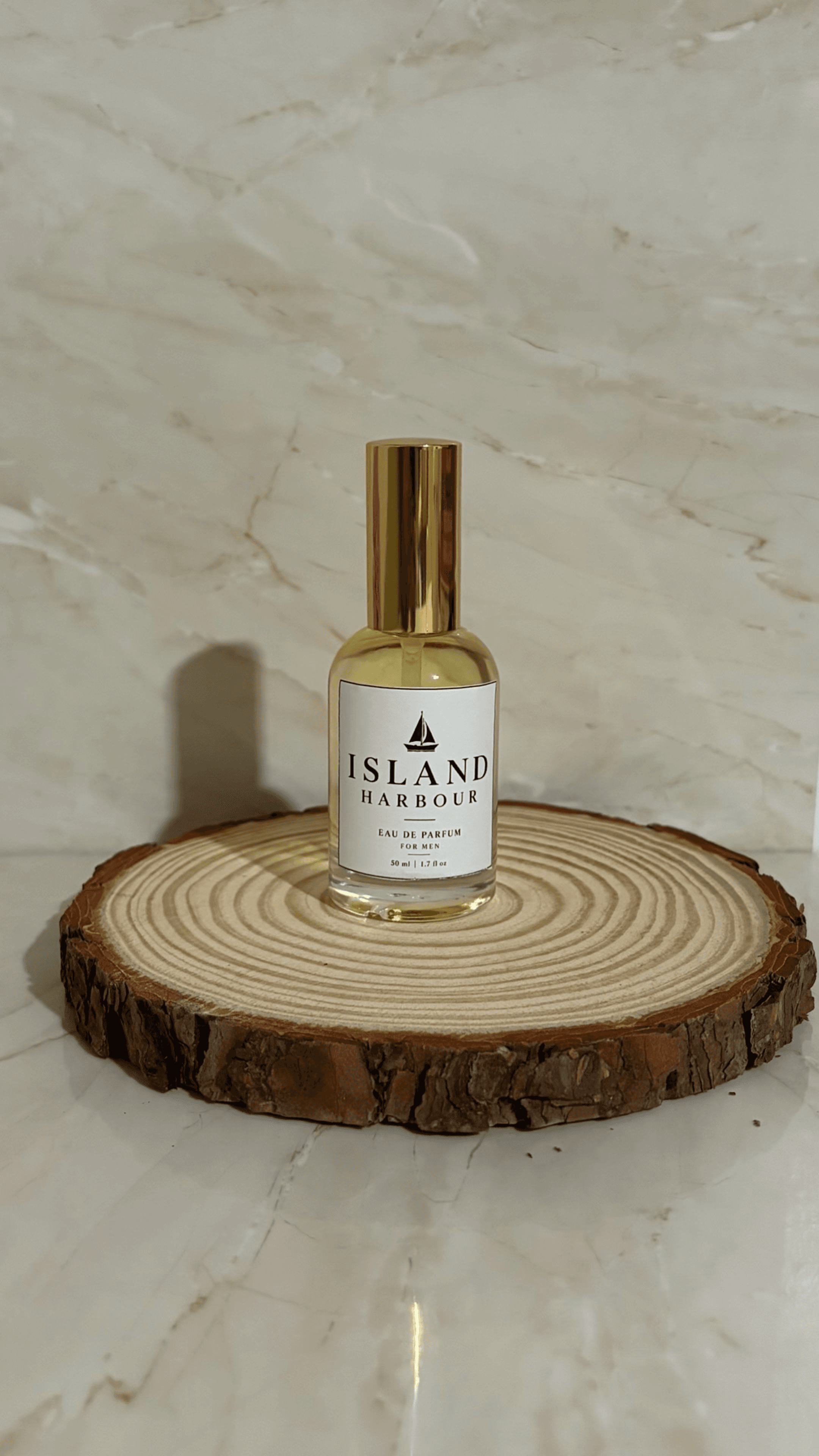 Island Harbour Eau de Parfum for Men held in daylight, showing the wooden cap and navy sailboat label